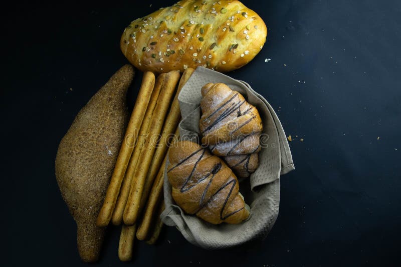 Different kinds of fresh Croissant and bread with grain on black rustic background stock images