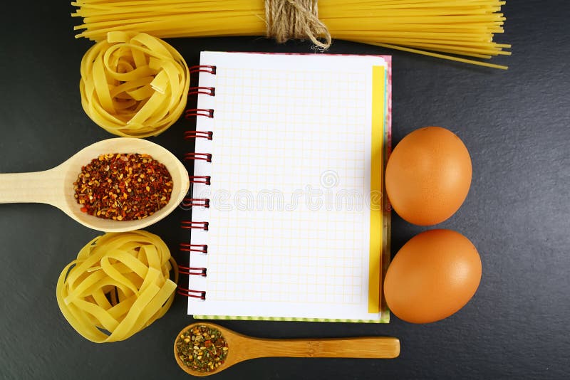 Different kinds of pasta tagliatelle, spaghetti, italian foods concept and menu design, spices on wooden spoons, raw eggs on a sha royalty free stock image Different kinds of pasta tagliatelle, spaghetti, italian foods concept and menu design, spices on wooden spoons, raw eggs on a sha royalty free stock image
