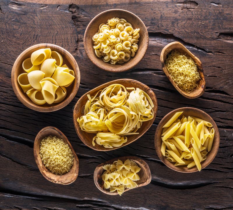 Different Pasta Types in Wooden Bowls on the Table. Top View Stock