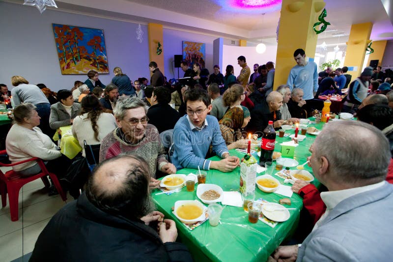 Different people talking at the tables at the Christmas charity dinner for the homeless stock image Different people talking at the tables at the Christmas charity dinner for the homeless stock image
