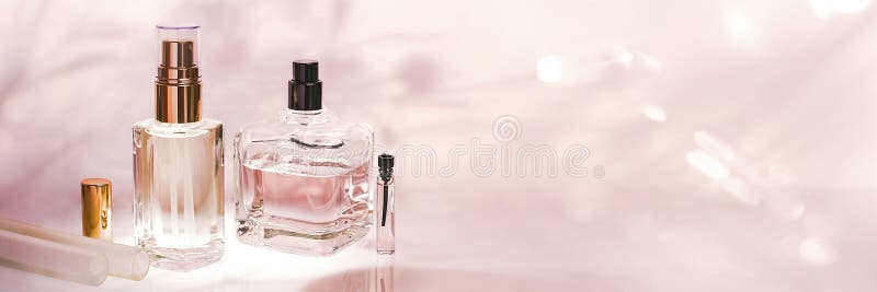 Different Perfume Bottles and Sampler on a Pink Floral Background