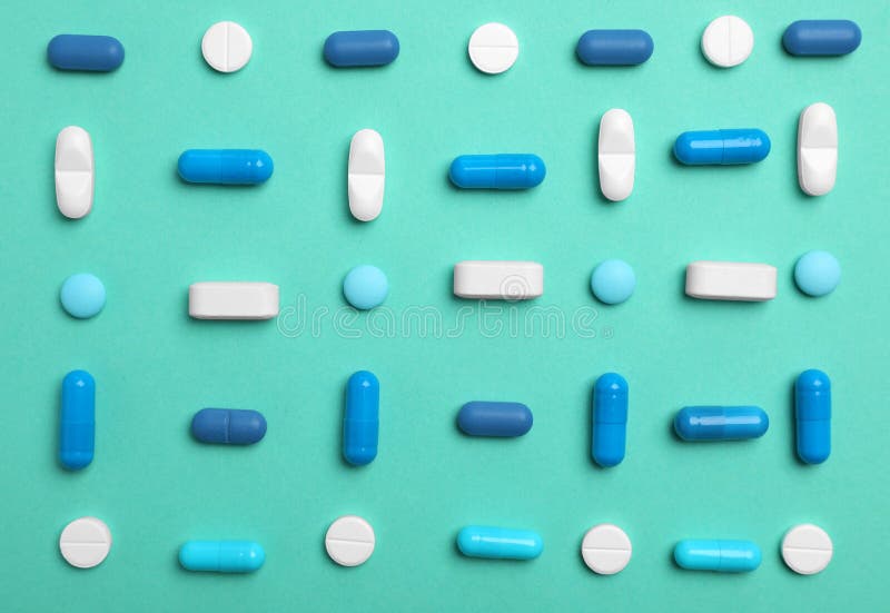 Different pills and capsules on color background