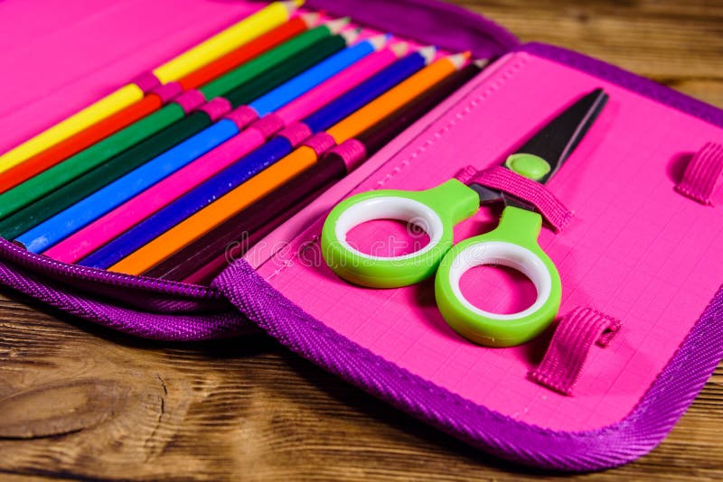 Different school stationeries pens, pencils and scissors in a pink pencil box