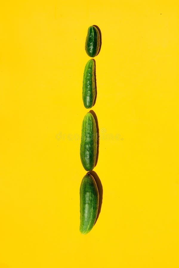 Different sizes forms cucumbers on a yellow background form a row royalty free stock photo Different sizes forms cucumbers on a yellow background form a row royalty free stock photo