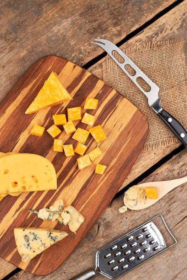 Different sorts of cheese on cutting board.