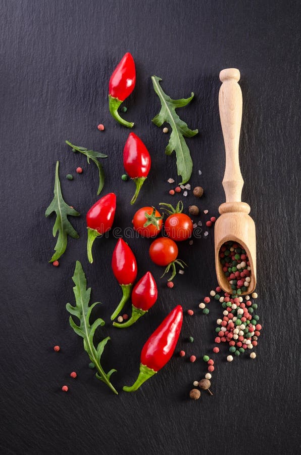 Different spices with tomato and peppers on black background