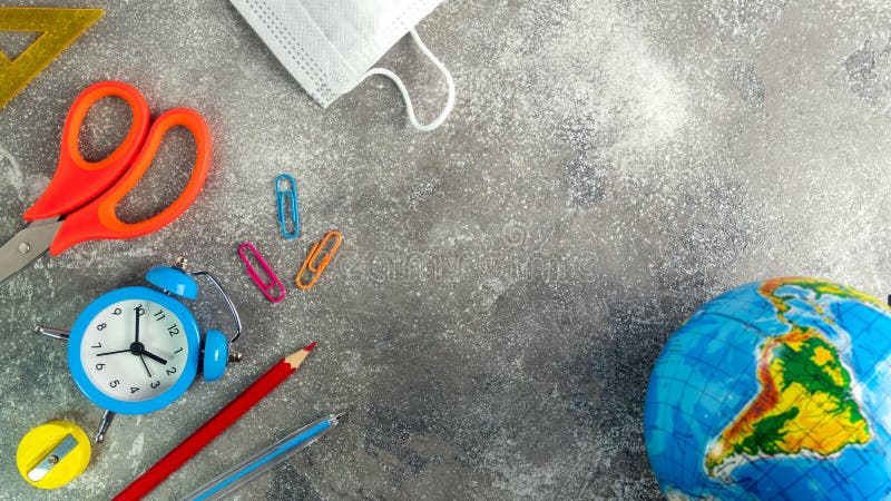 Different stationery, blue alarm clock and medical mask. Set of school supplies during coronavirus time. Learning at home. Back royalty free stock image.