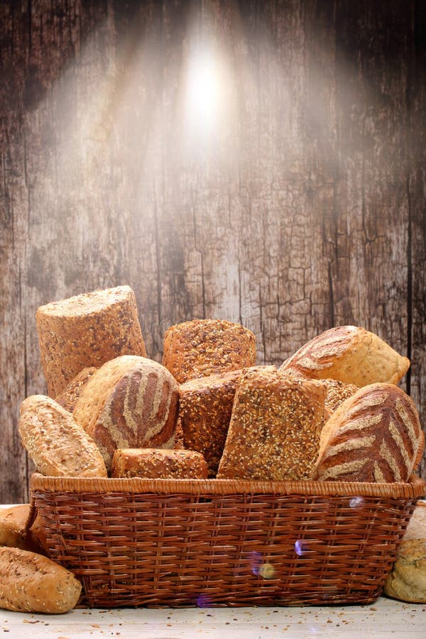 Different Types of Bread and Buns in a Willow Basket on a Wooden
