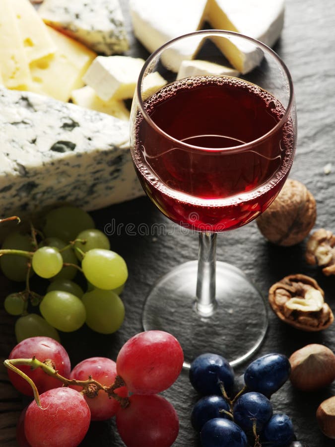Different types of cheeses with wine glass and fruits. stock image