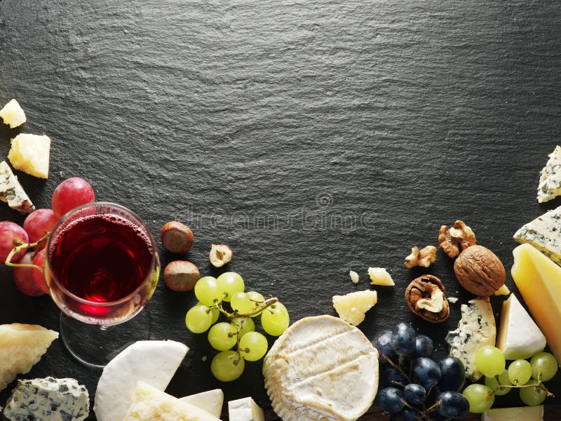 Different types of cheeses with wine glass and fruits. stock photo