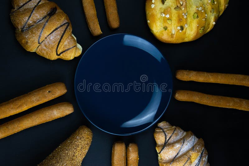 Different types of fresh bread with grain on a black rustic background. the bread stands around blue plate stock photo