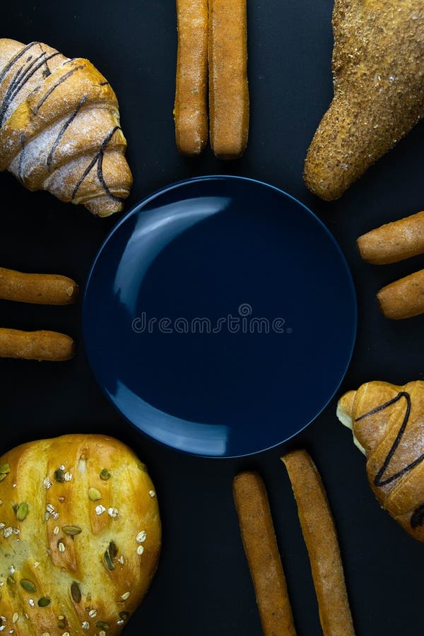 Different types of fresh bread with grain on a black rustic background. the bread stands around blue plate stock photo