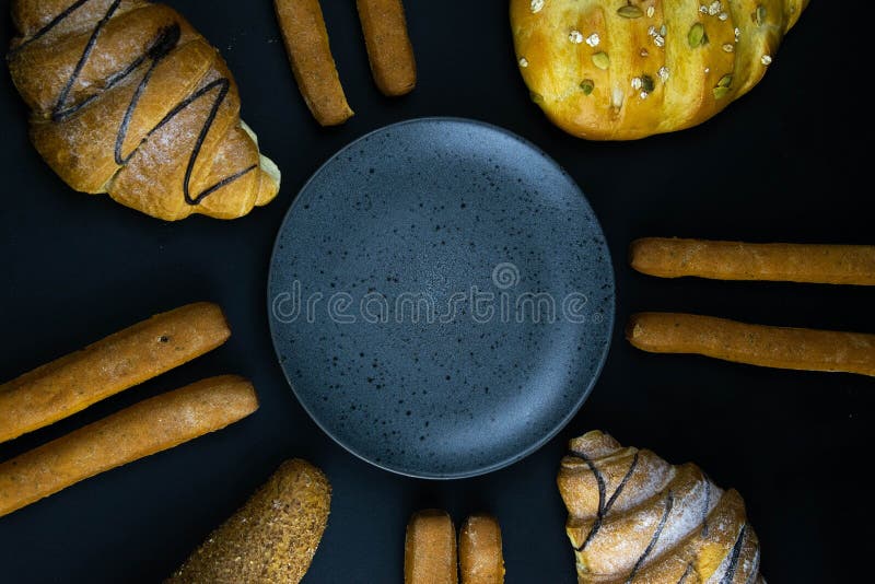 Different types of fresh bread with grain on a black rustic background. the bread stands around grey plate royalty free stock photos