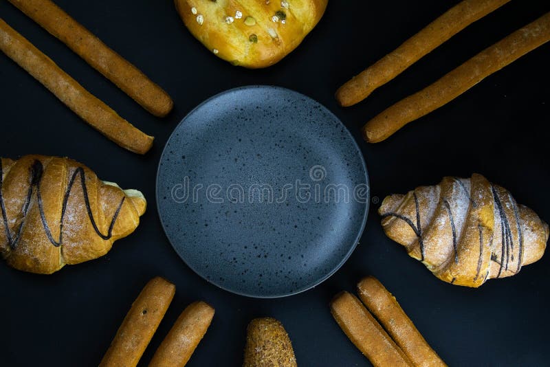 Different types of fresh bread with grain on a black rustic background. the bread stands around grey plate royalty free stock images
