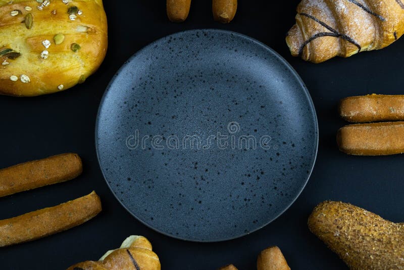 Different types of fresh bread with grain on a black rustic background. the bread stands around grey plate stock image