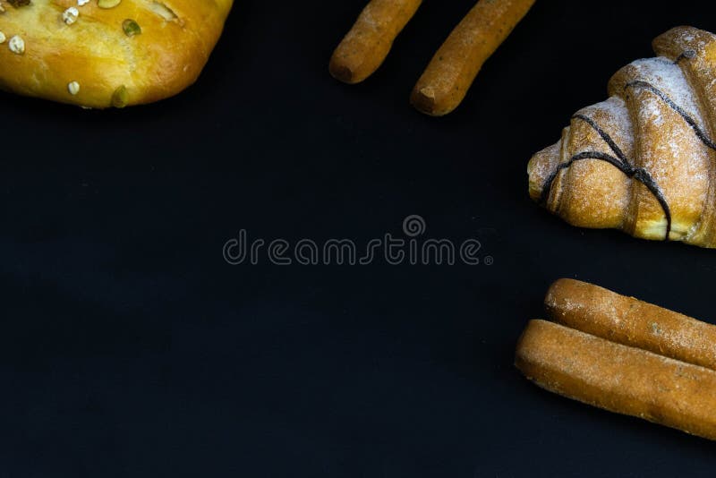 Different types of fresh bread with grain on a black rustic background. the bread stands around on top position royalty free stock photography