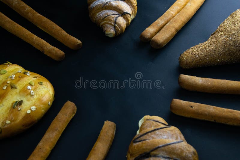Different types of fresh bread with grain on a black rustic background. the bread stands around on top position royalty free stock photo