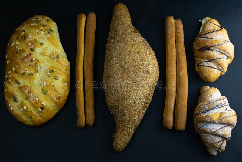 Different types of fresh bread with grain on a black rustic background. bread stands in one horizontal row stock photo