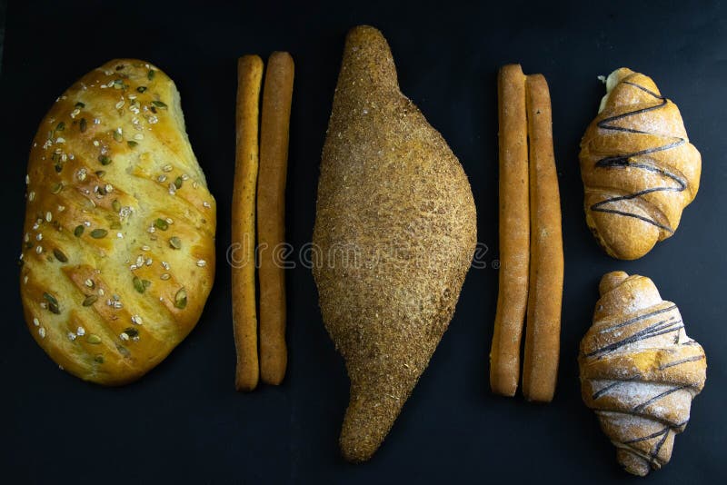 Different types of fresh bread with grain on a black rustic background. bread stands in one horizontal row royalty free stock images