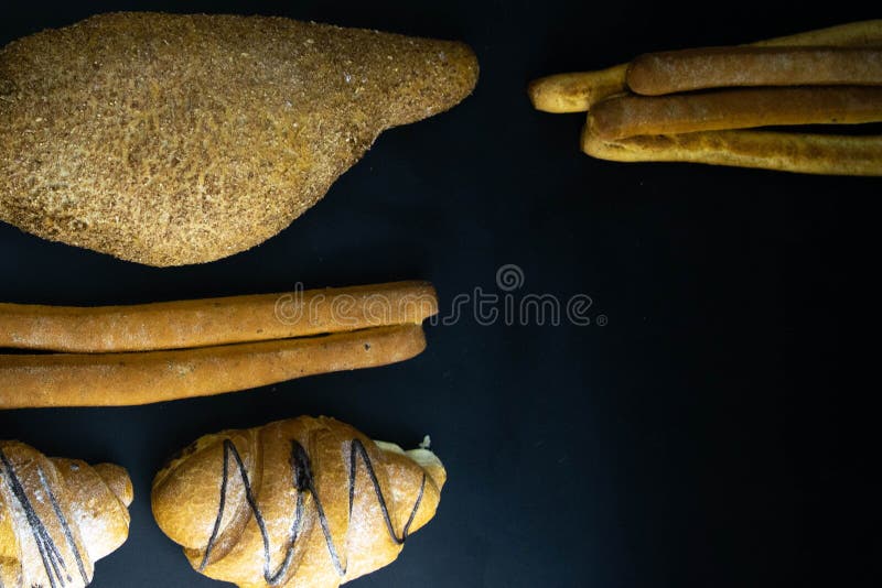 Different types of fresh bread with grain on a black rustic background. bread stands in one vertical row stock images