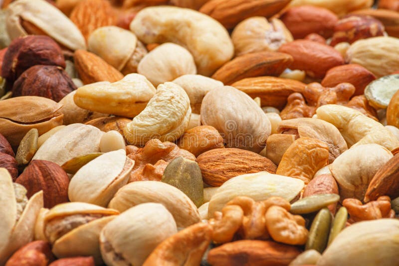 Different types of nuts and seeds, photo with selective focus. Peeled walnut, hazelnuts, peeled peanut, pine nut kernels, almond seeds, cashew seeds, pistachio nuts in the shell, pumpkin seeds