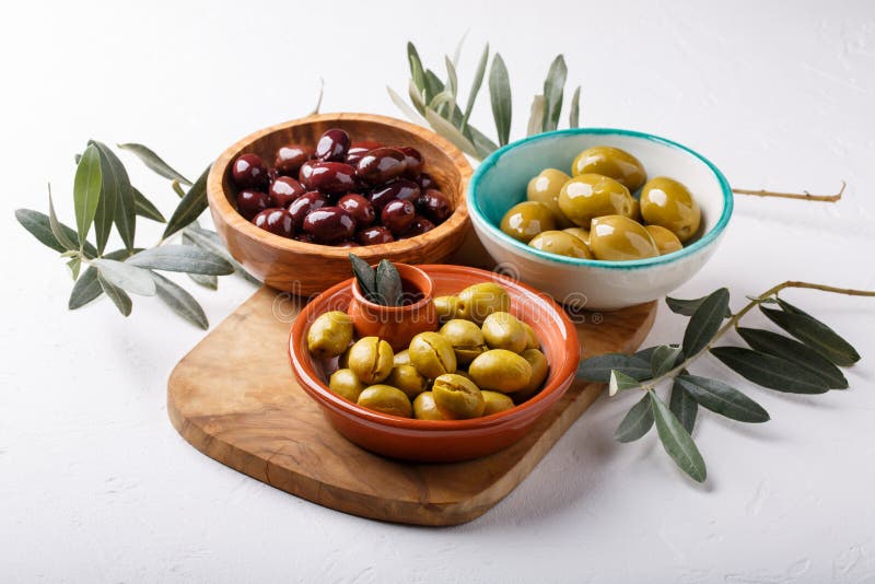 Different Types of Olives Green and Black in Bowls on White Table Stock