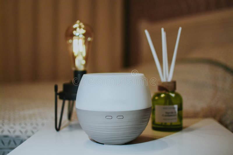 Diffusore di olio di Aroma e fragranze domestiche sullo sfondo di una lampada da tavola nella camera da letto. L'aromaterapia favorisce il buon sonno e l'aria fresca nella stanza. Immagini di alta qualità