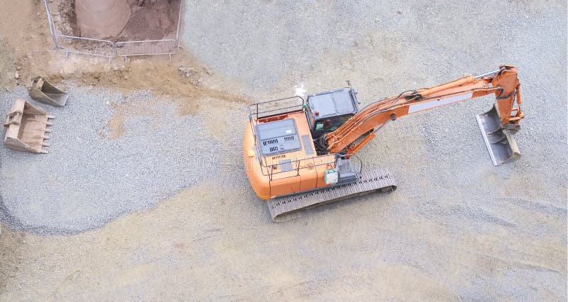 Digger excavator construction building site view from above miniature rubber tracks orange vehicle in operation excavating banner uk