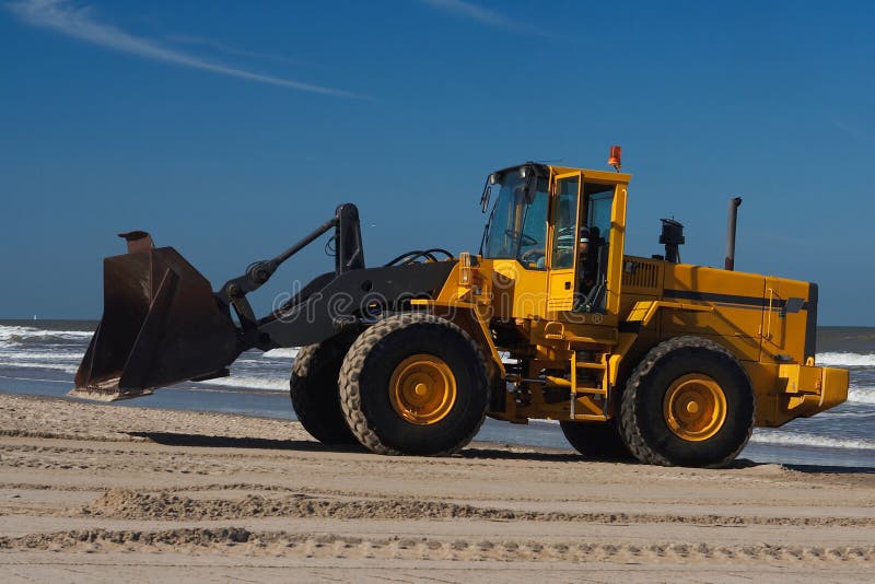 Action shot of an orange digger moving earth working at the beach. Action shot of an orange digger moving earth working at the beach.