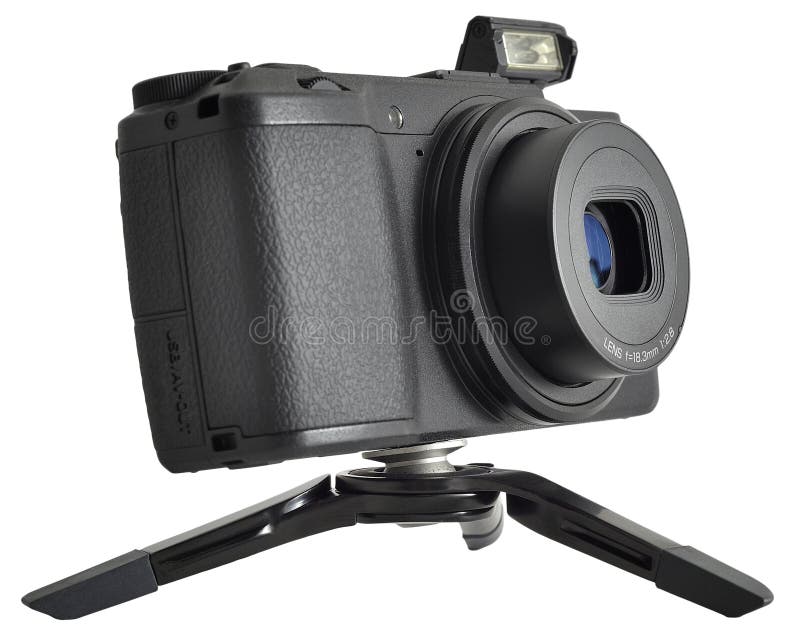 Classic black digital compact camera power-on opening its flash and stands by a mini desk tripod isolated on white