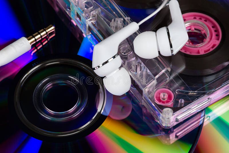 White earbuds on CD's and analog audio tape cassette background. White earbuds on CD's and analog audio tape cassette background.