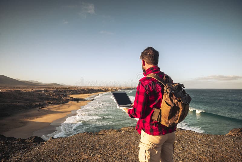 Digital nomad people smart working concept with standing man work with laptop computer and internet connection roaming in wild