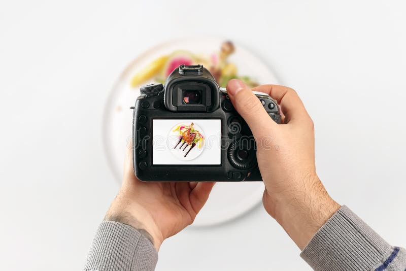 Digital single-lens reflex camera in hands. Man photographer makes photos. Male hands hold the camera close-up