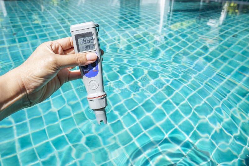 Digital waterproof and temp pocket tester in girl hand over blue swimming pool water