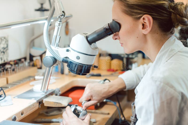 Diligent Jeweler Working on Microscope at Her Workbench Stock Image