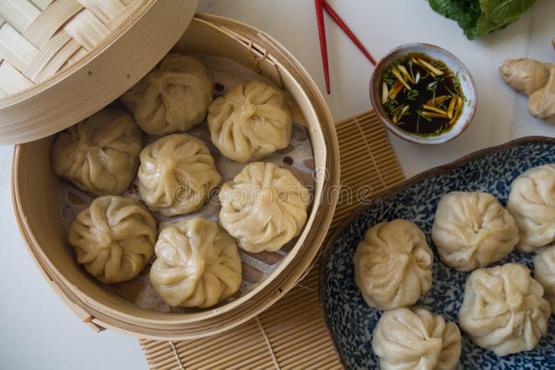 Dim sum aka dumplings,momos in a traditional bamboo steamer, with red chopsticks, Chinese cabbage & ginger root against white ba royalty free stock image Dim sum aka dumplings,momos in a traditional bamboo steamer, with red chopsticks, Chinese cabbage & ginger root against white ba royalty free stock image