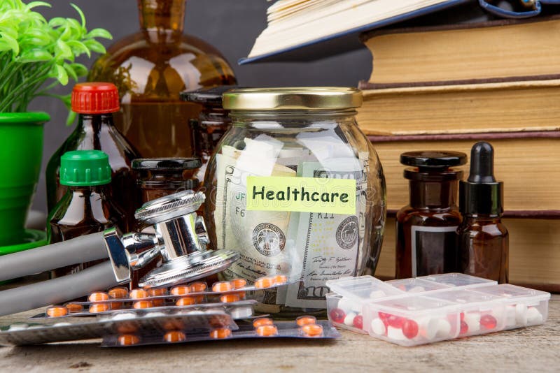Dinero para el seguro de la atención sanitaria - vidrio, estetoscopio, píldoras y botellas del ahorro del dinero imágenes de archivo libres de regalías Dinero para el seguro de la atención sanitaria - vidrio, estetoscopio, píldoras y botellas del ahorro del dinero imágenes de archivo libres de regalías