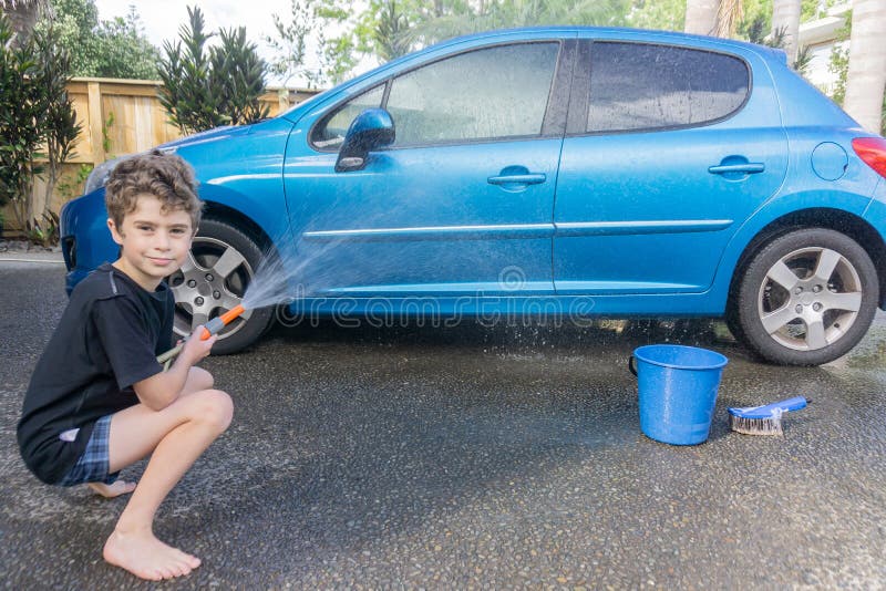 Dinero suelto de la ganancia del muchacho que limpia el coche compacto azul fotos de archivo