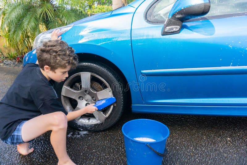 Dinero suelto de la ganancia del muchacho que limpia el coche compacto azul foto de archivo