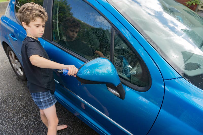 Dinero suelto de la ganancia del muchacho que limpia el coche compacto azul imagen de archivo