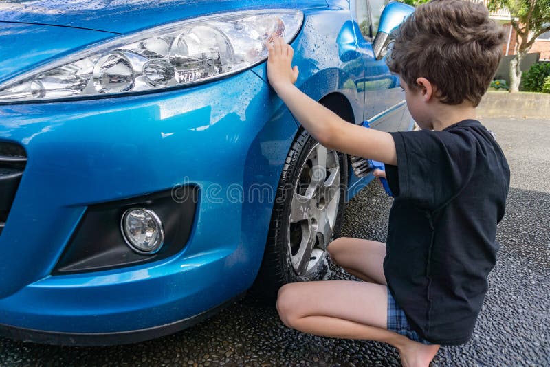 Dinero suelto de la ganancia del muchacho que limpia el coche compacto azul imagenes de archivo