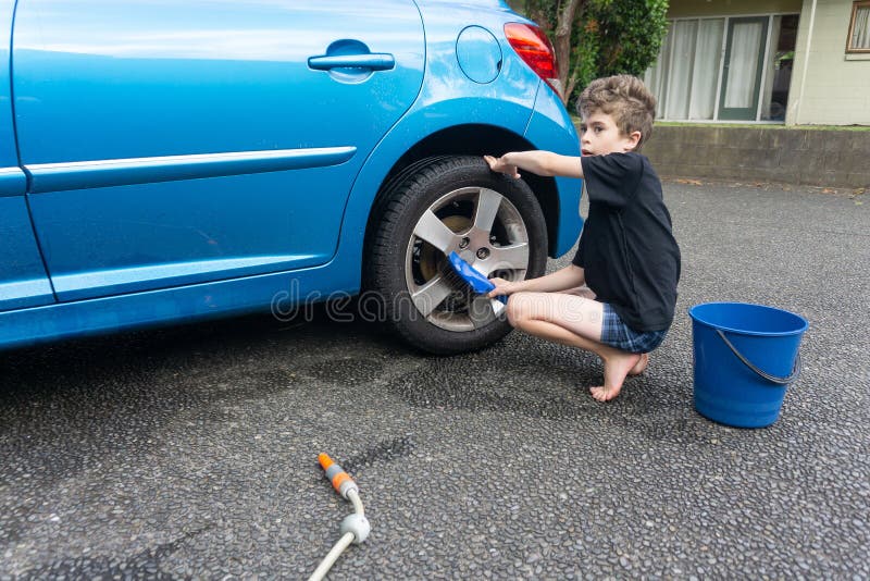 Dinero suelto de la ganancia del muchacho que limpia el coche compacto azul imagen de archivo