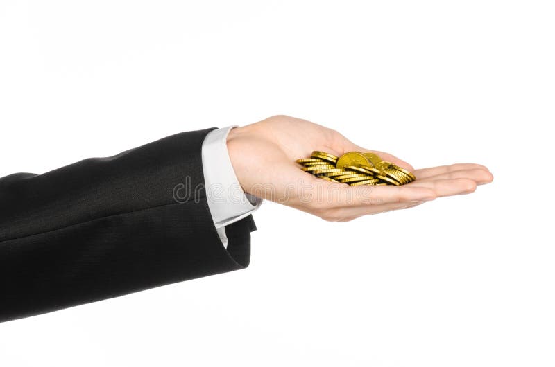 Dinheiro e assunto do negócio: mão em um terno preto que mantém uma pilha de moedas de ouro no estúdio em um fundo branco isolada fotografia de stock royalty free Dinheiro e assunto do negócio: mão em um terno preto que mantém uma pilha de moedas de ouro no estúdio em um fundo branco isolada fotografia de stock royalty free