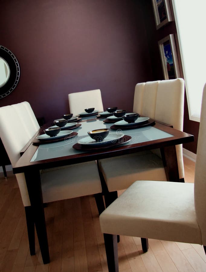 Dining Room. Elegant, contemporary dining table in chocolate brown and blue, with matching dinnerware. Cream chairs with wooden legs, hardwood floor Dining Room. Elegant, contemporary dining table in chocolate brown and blue, with matching dinnerware. Cream chairs with wooden legs, hardwood floor