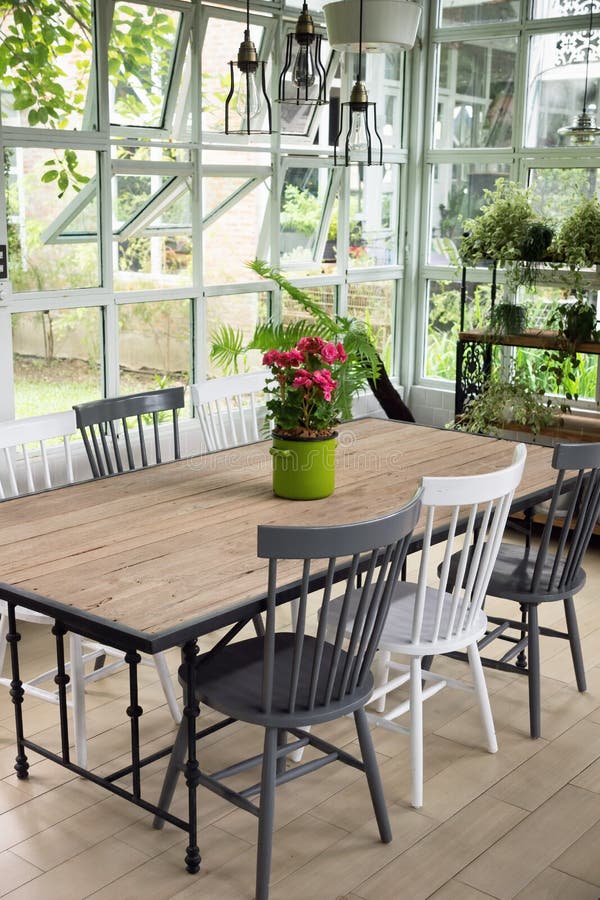 Dining room interior with table, chairs and plants against big w