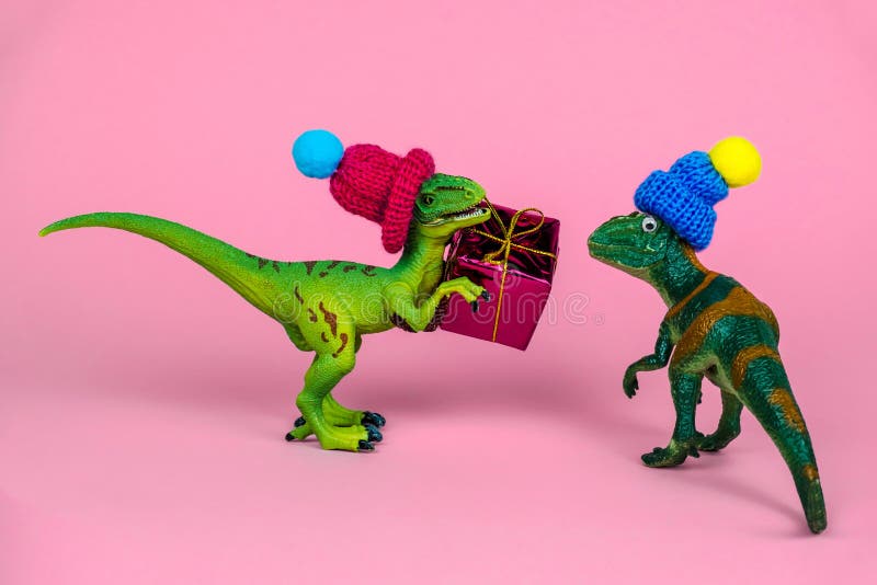 Dinossauro de brinquedo verde de malha que dá caixa de presente a outro dinossauro nesse cartão de saudação engraçado festivo