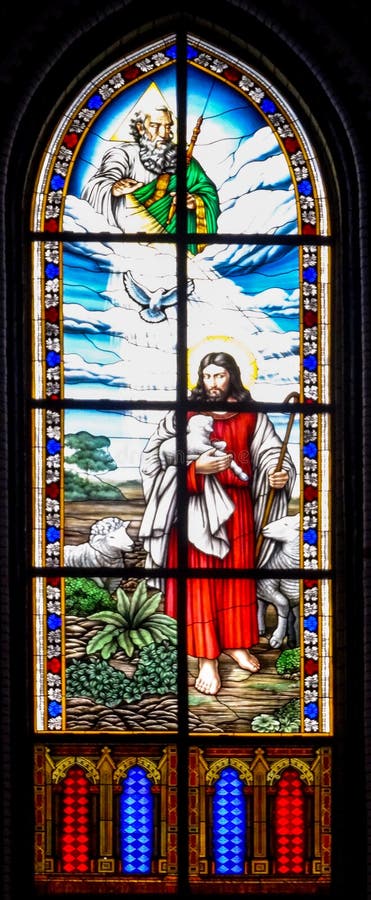 Jesus holding a lamb with god above in a stained glass window. Jesus holding a lamb with god above in a stained glass window