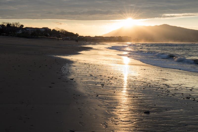 Direct golden sunset`s sunlight on a scenic sandy beach in hendaye in dramatic cloudy atmosphere, basque country, france. Direct golden sunset`s sunlight on a royalty free stock photos Direct golden sunset`s sunlight on a scenic sandy beach in hendaye in dramatic cloudy atmosphere, basque country, france. Direct golden sunset`s sunlight on a royalty free stock photos
