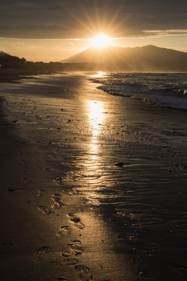 Direct golden sunset`s sunlight on a scenic sandy beach in hendaye in dramatic cloudy atmosphere, basque country, france. Direct golden sunset`s sunlight on a stock photography Direct golden sunset`s sunlight on a scenic sandy beach in hendaye in dramatic cloudy atmosphere, basque country, france. Direct golden sunset`s sunlight on a stock photography