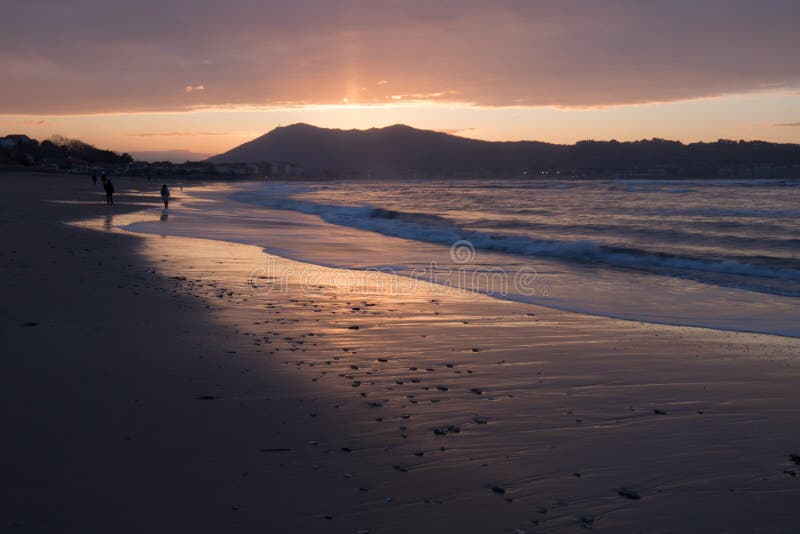 Direct golden sunset`s sunlight on a scenic sandy beach in hendaye in dramatic cloudy atmosphere, basque country, france. Direct golden sunset`s sunlight on a royalty free stock photo Direct golden sunset`s sunlight on a scenic sandy beach in hendaye in dramatic cloudy atmosphere, basque country, france. Direct golden sunset`s sunlight on a royalty free stock photo